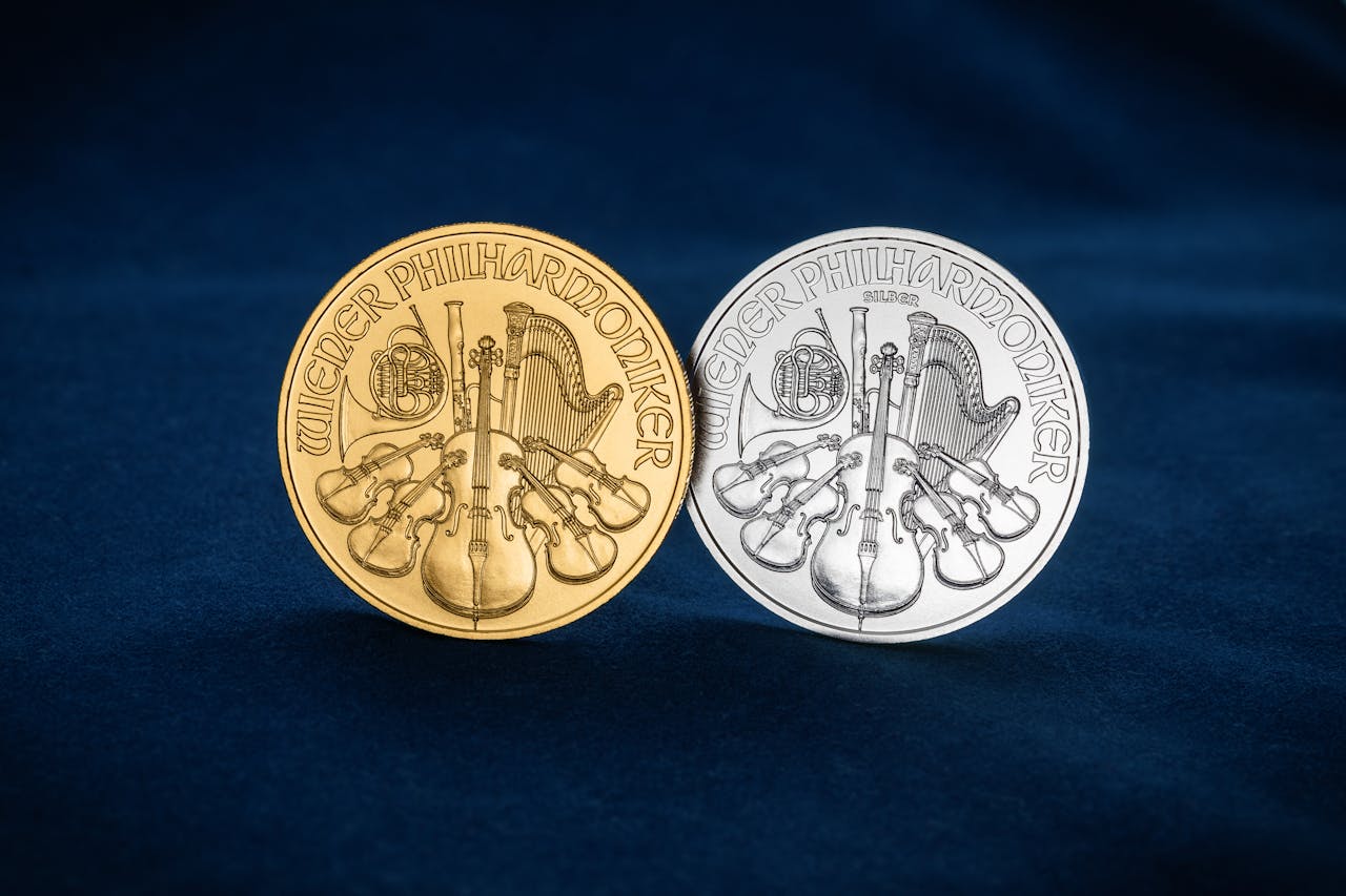 Close-up of gold and silver Wiener Philharmoniker coins displayed on blue velvet cloth.